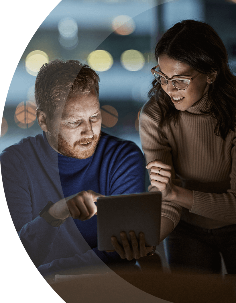 two IT employees looking at a tablet in the office at night